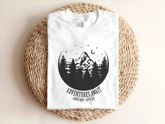 Adult graphic t-shirt featuring “Adventures Await” design with mountain and forest scene, perfect unisex tee for outdoor and travel lovers.